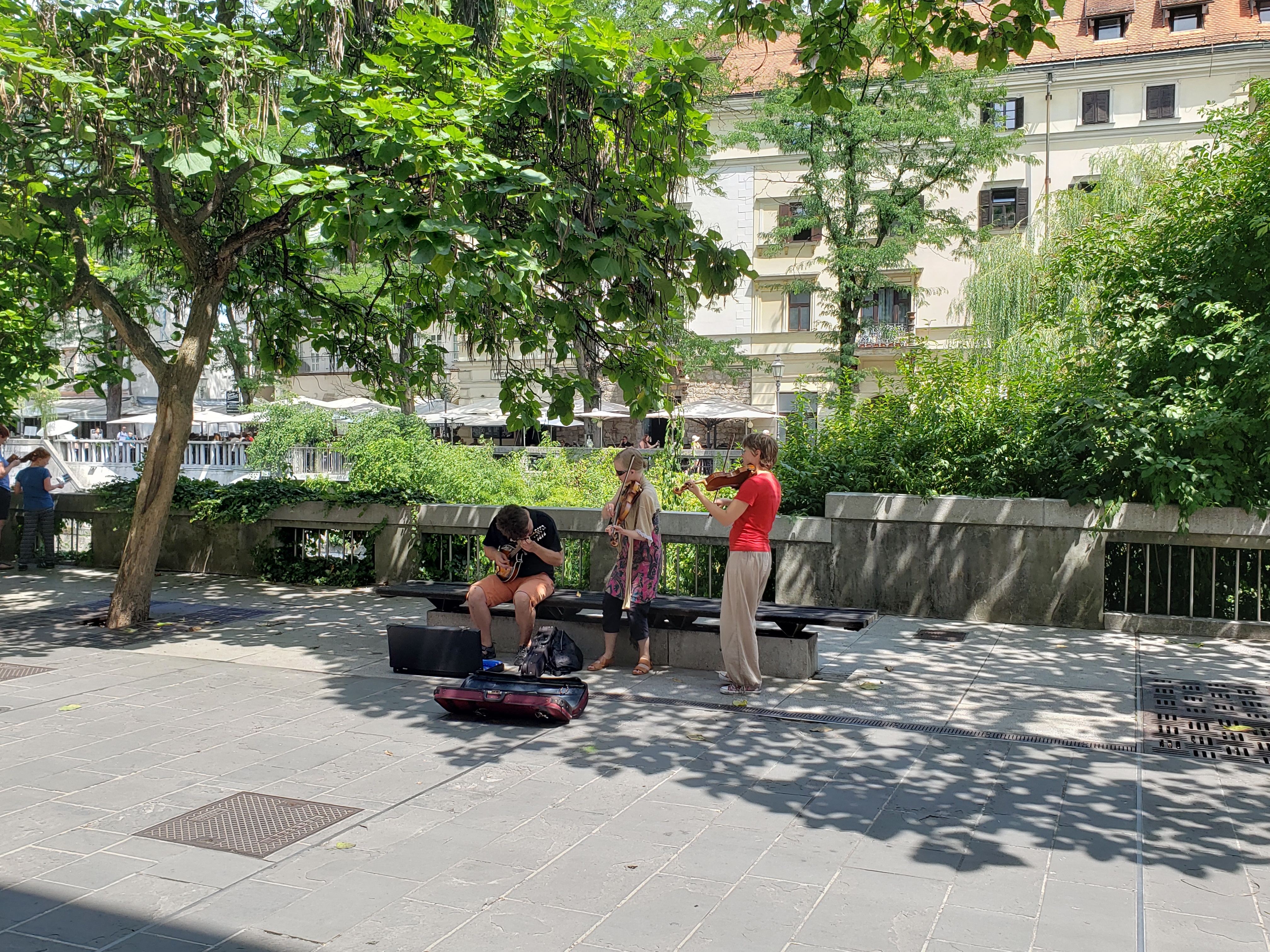center of photo shows 3 musicians, one seated playing what a mandolin, maybe? Two women standing are playing violins or fiddles - is there a difference?