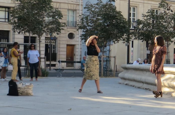 Girl modeling with a small group of people watching her and the photographer