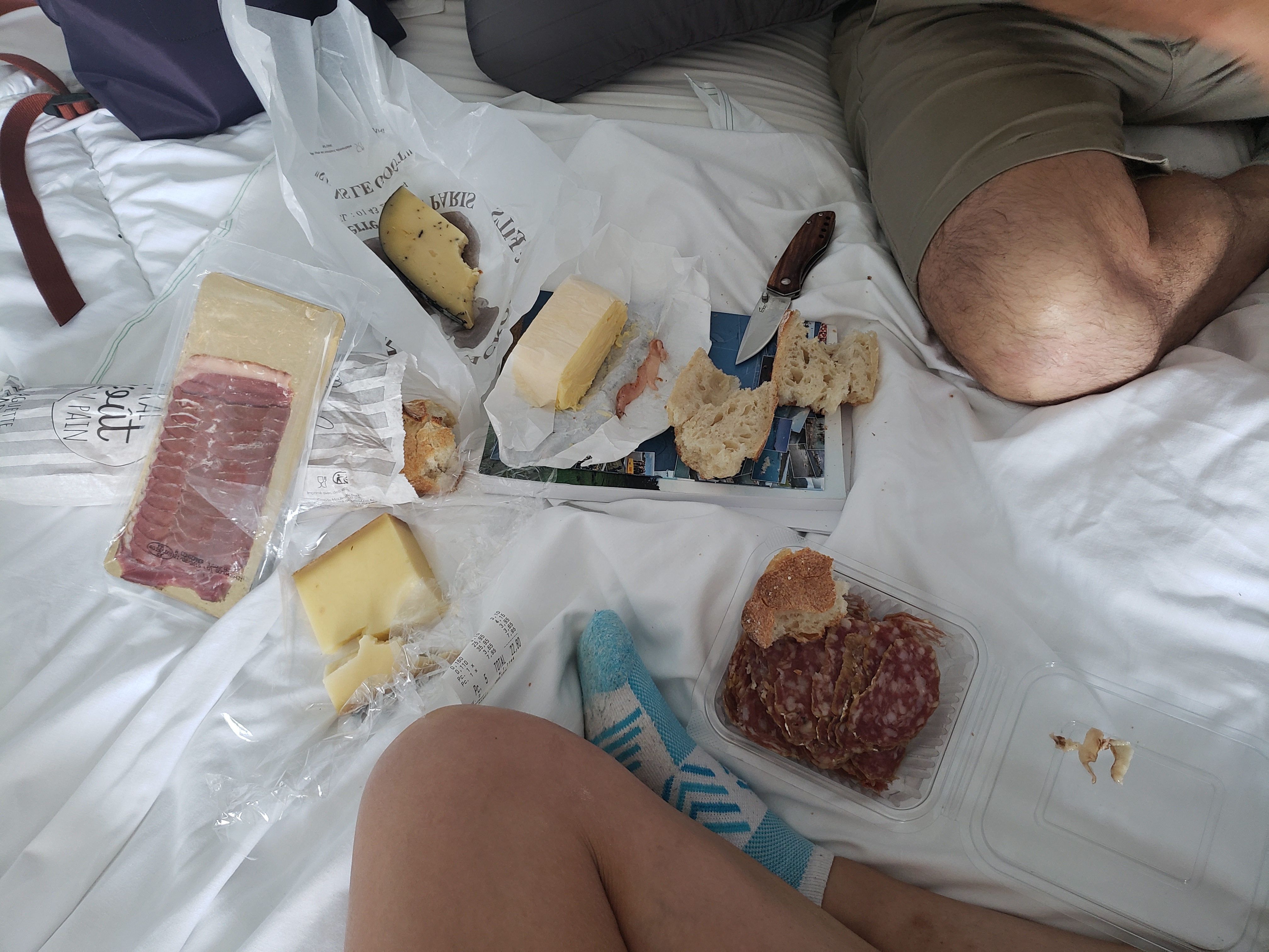 little smorgasbord of cheeses, meats, butter, and bread spread out on our bed with my knee on the bottom of the photo and Patrick's kneed on the top right corner.