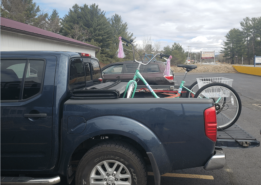 Blue truck with a trike strapped down in the truck bed.