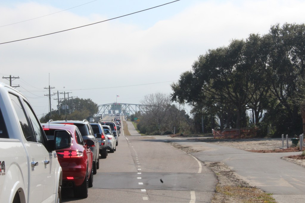 View of the Ben Sawyer Memorial Bridge swung open to allow a boat pass through.  In the foreground is a row of cars queuing up to go over the bridge.